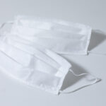close up view of of two white face masks against coronavirus covid19 pandemic, on white background.